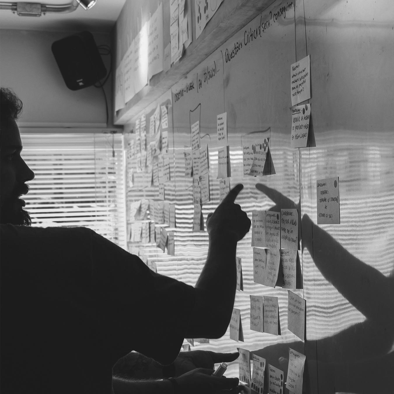 A man stood in front of a white board covered in post-it notes, pointing at the board.